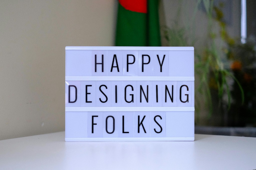 Lightbox on a desk that reads Happy Designing Folks.